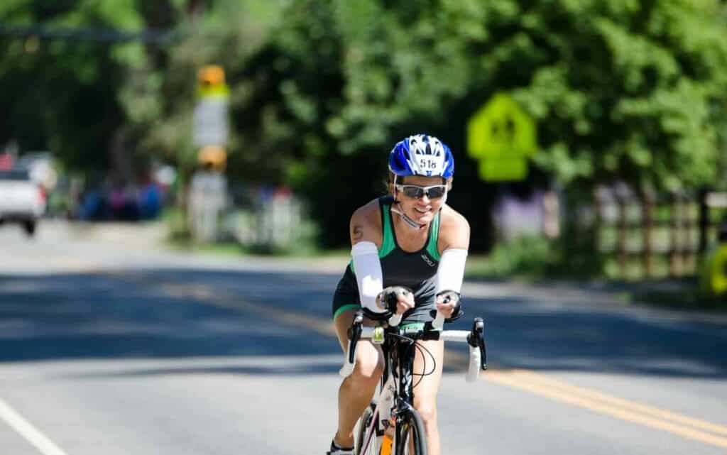 man in blue and white bicycle helmet riding on black road bike during daytime